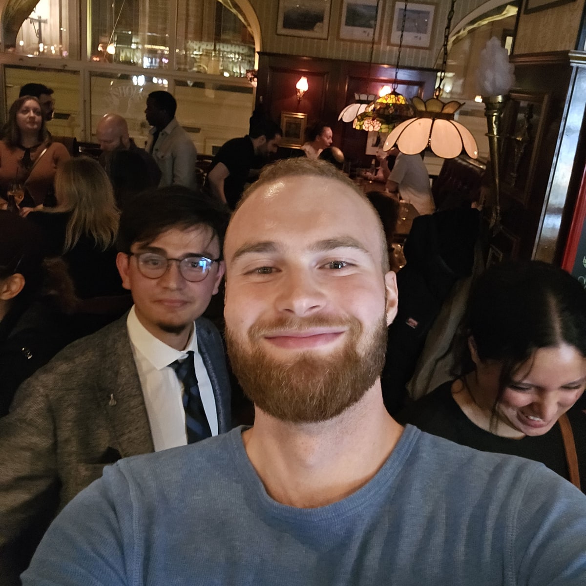 Tristan Rune Gyllensvärd-Jülich taking a selfie with attendees at a Meet Stockholm Thursday pub gathering.